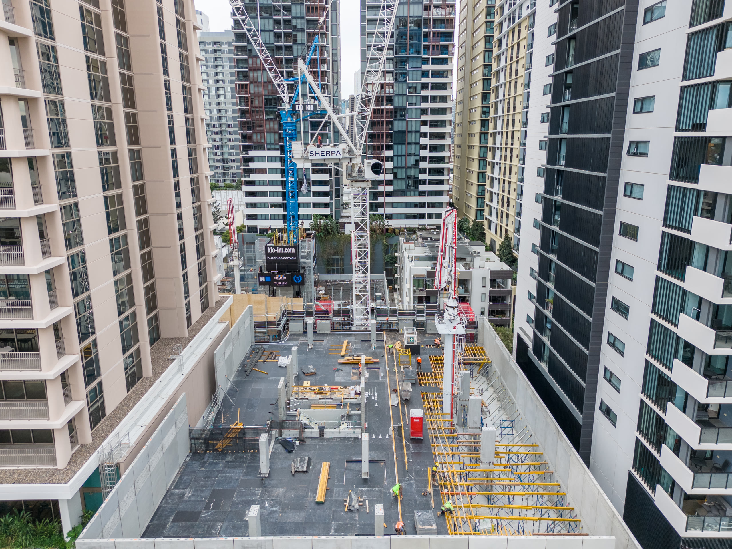 Deck level view across a Brisbane build, cranes and city behind